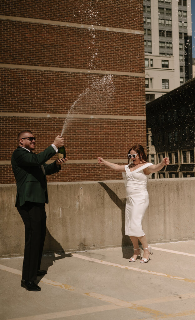 Couple popping champagne for their Philadelphia elopement photos on a rooftop
