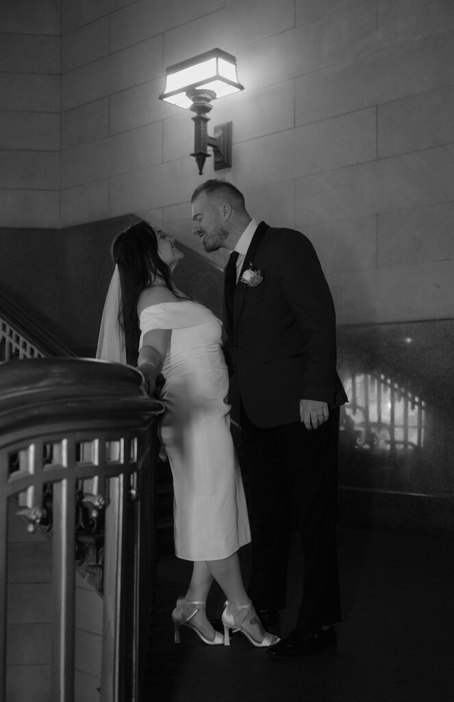 Black and white photo of a bride and groom posing on a staircase for their Philadelphia City Hall wedding photos