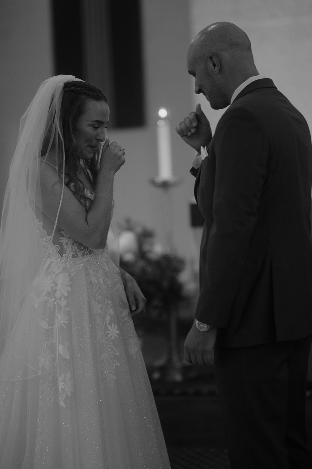 Bride and groom wiping tears during Catholic vows — storytelling wedding photography emotional moment.