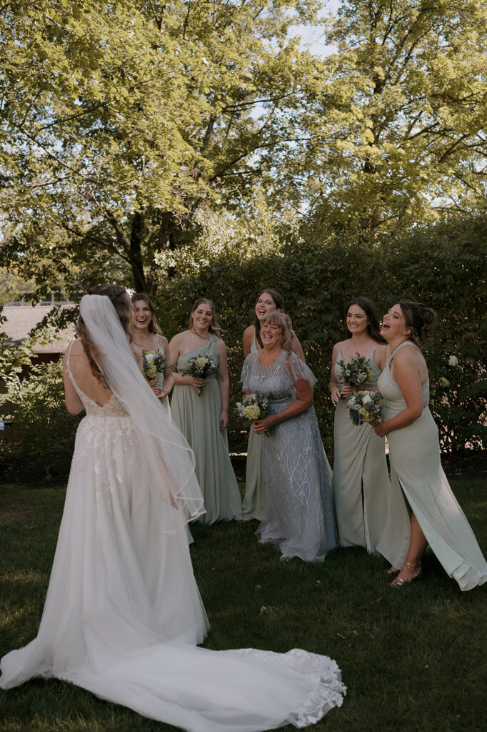 Bride laughing with bridesmaids and mother, group portrait full of joy at The Inn at Millrace Pond wedding.