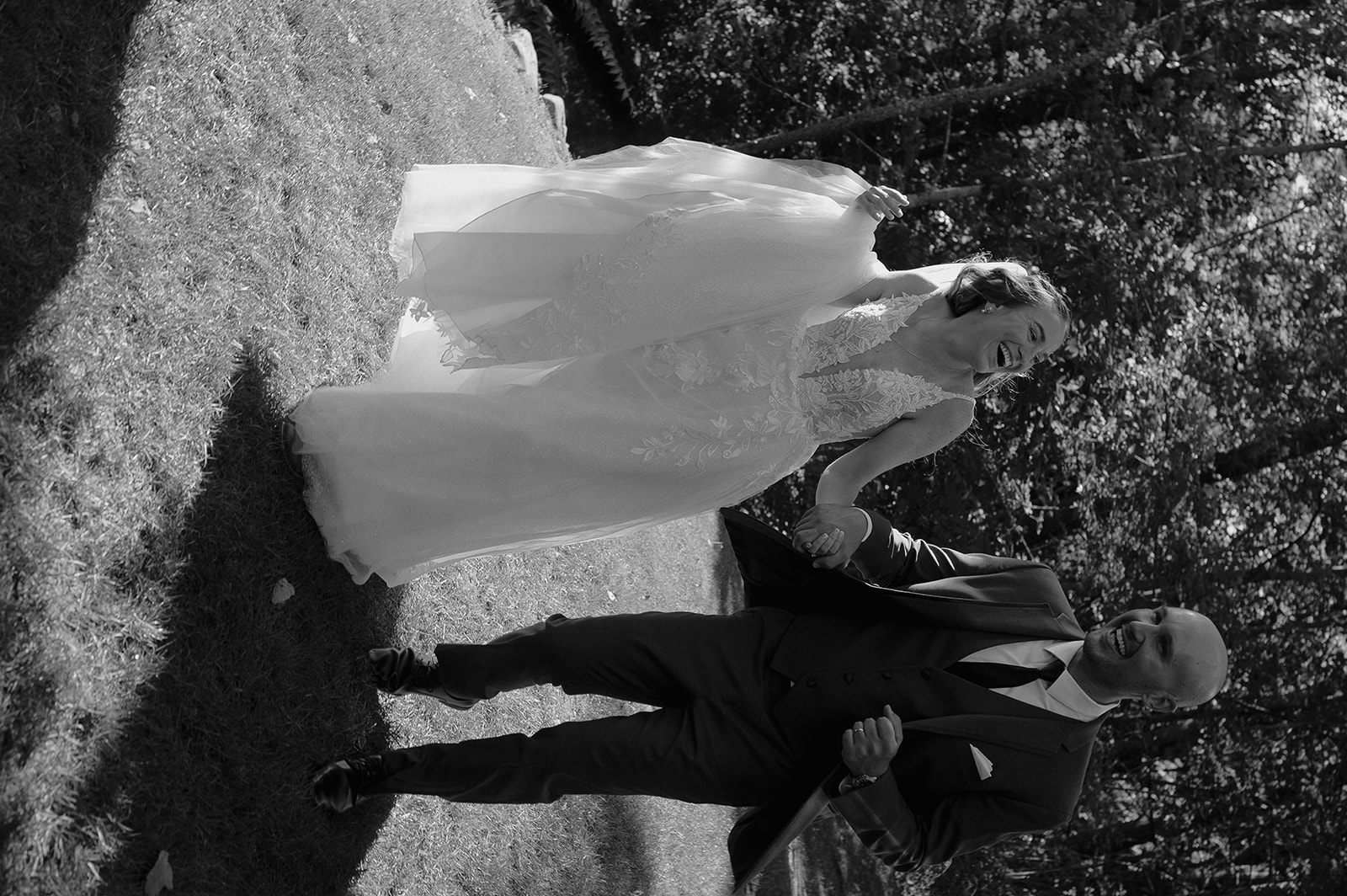 Black and white photo of a bride and groom laughing together at The Inn at Millrace Pond