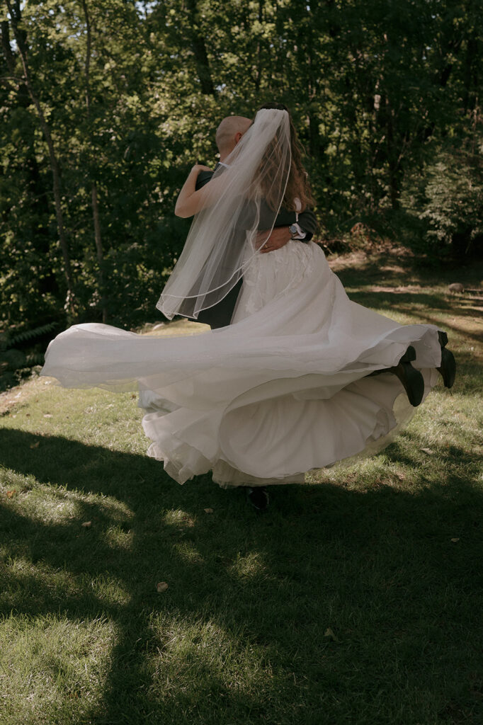 Bride lifting and twirling his bride during their The Inn at Millrace Pond wedding portraits