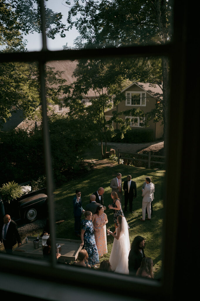 Window photo of guests enjoying cocktail hour at The Inn at Millrace Pond