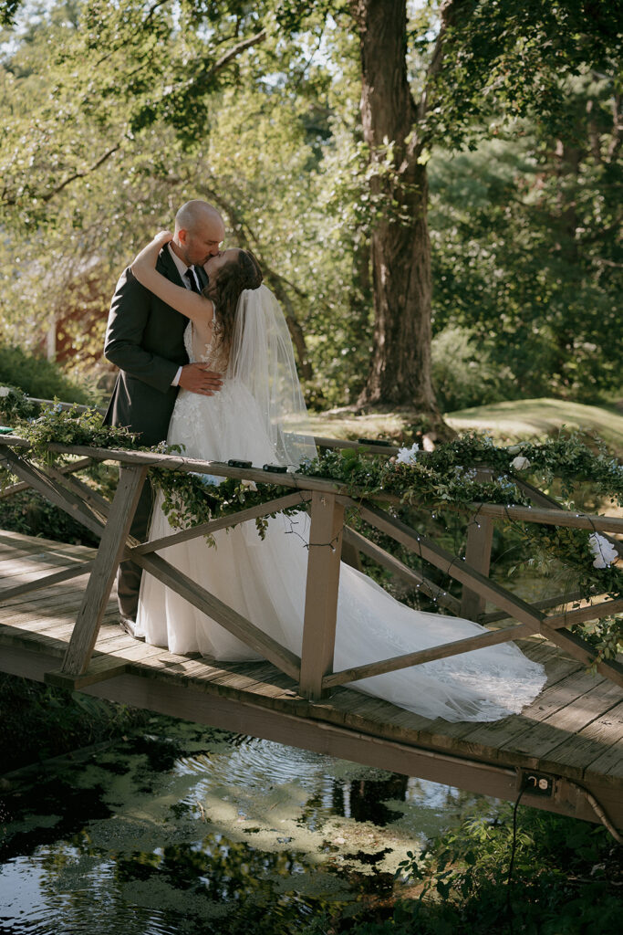 Bride and groom kissing on a bridge at The Inn at Millrace Pond wedding venue