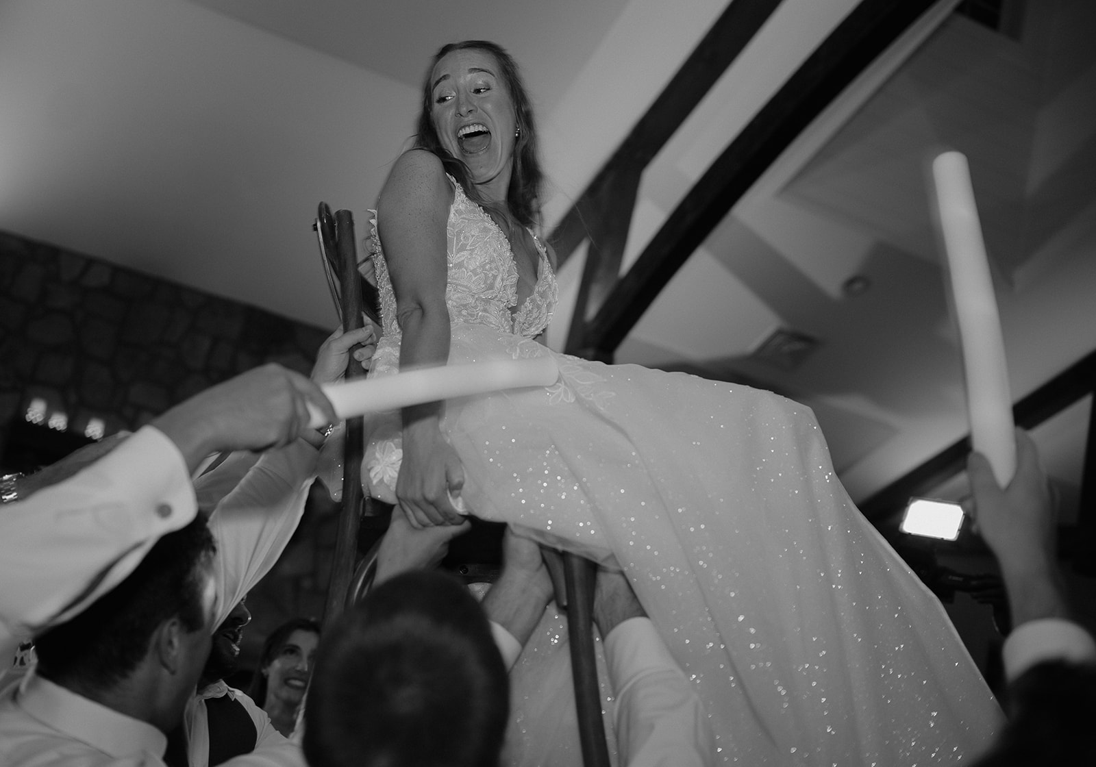 Bride lifted into the air on chair during The Inn at Millrace Pond barn wedding reception.