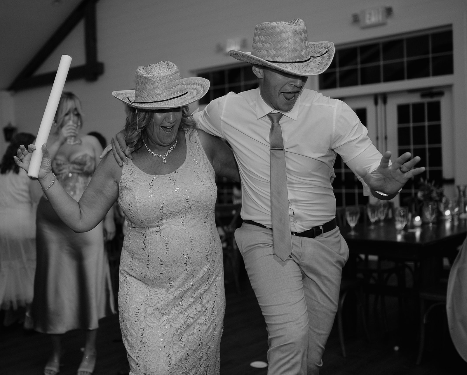 Black and white photo of guests wearing hats and dancing during the reception