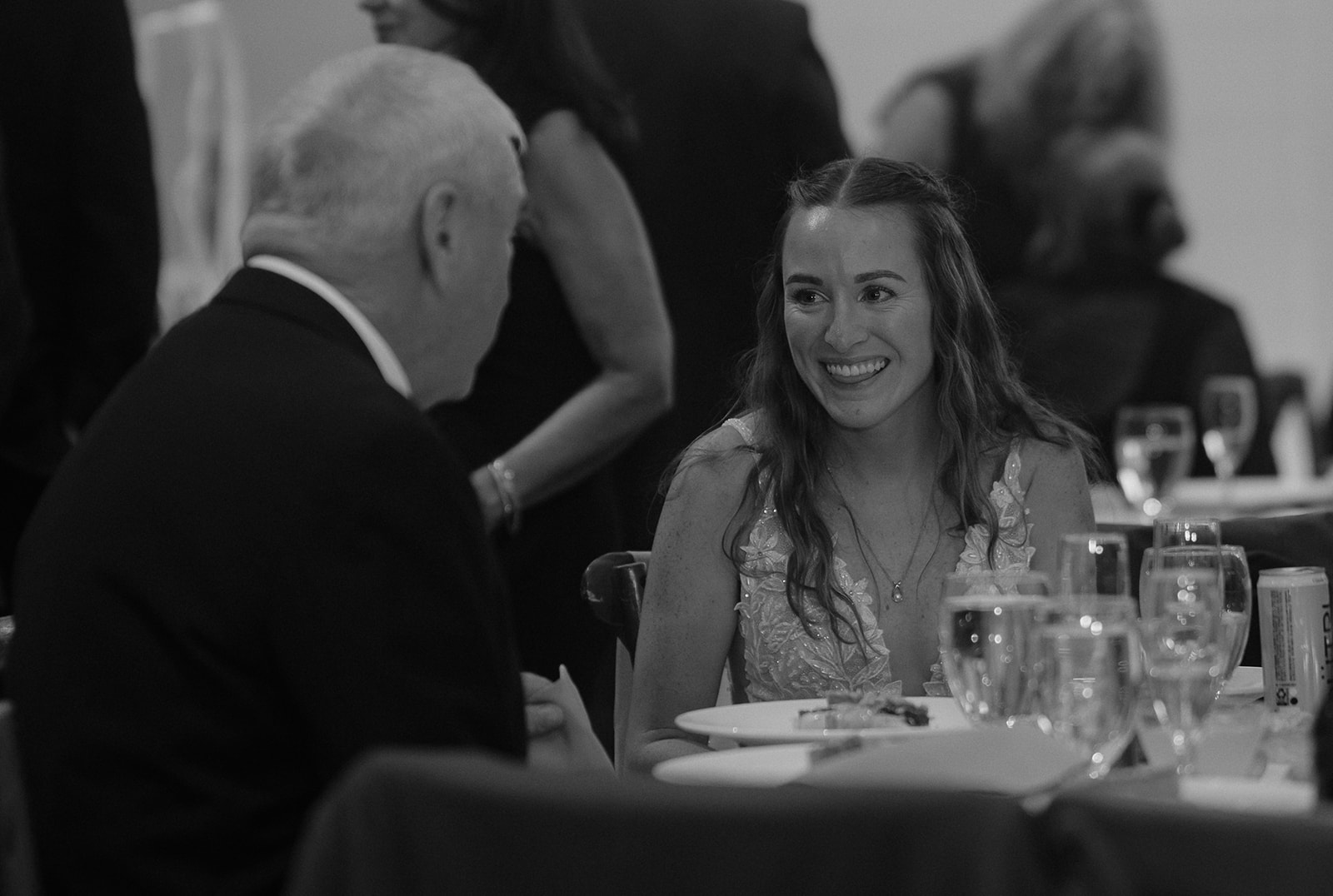 Bride smiling warmly at guest during reception dinner conversation at The Inn at Millrace Pond wedding.