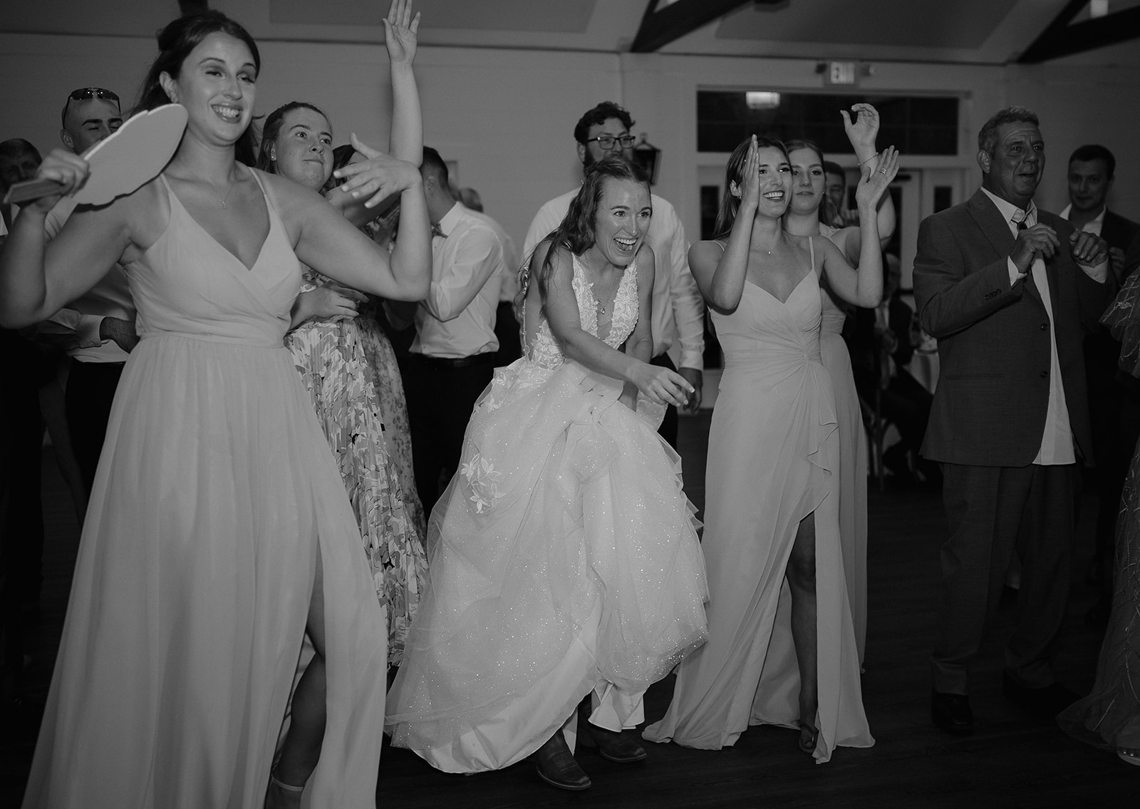 Bride and bridesmaids dancing with joy on the dance floor during barn reception at The Inn at Millrace Pond.