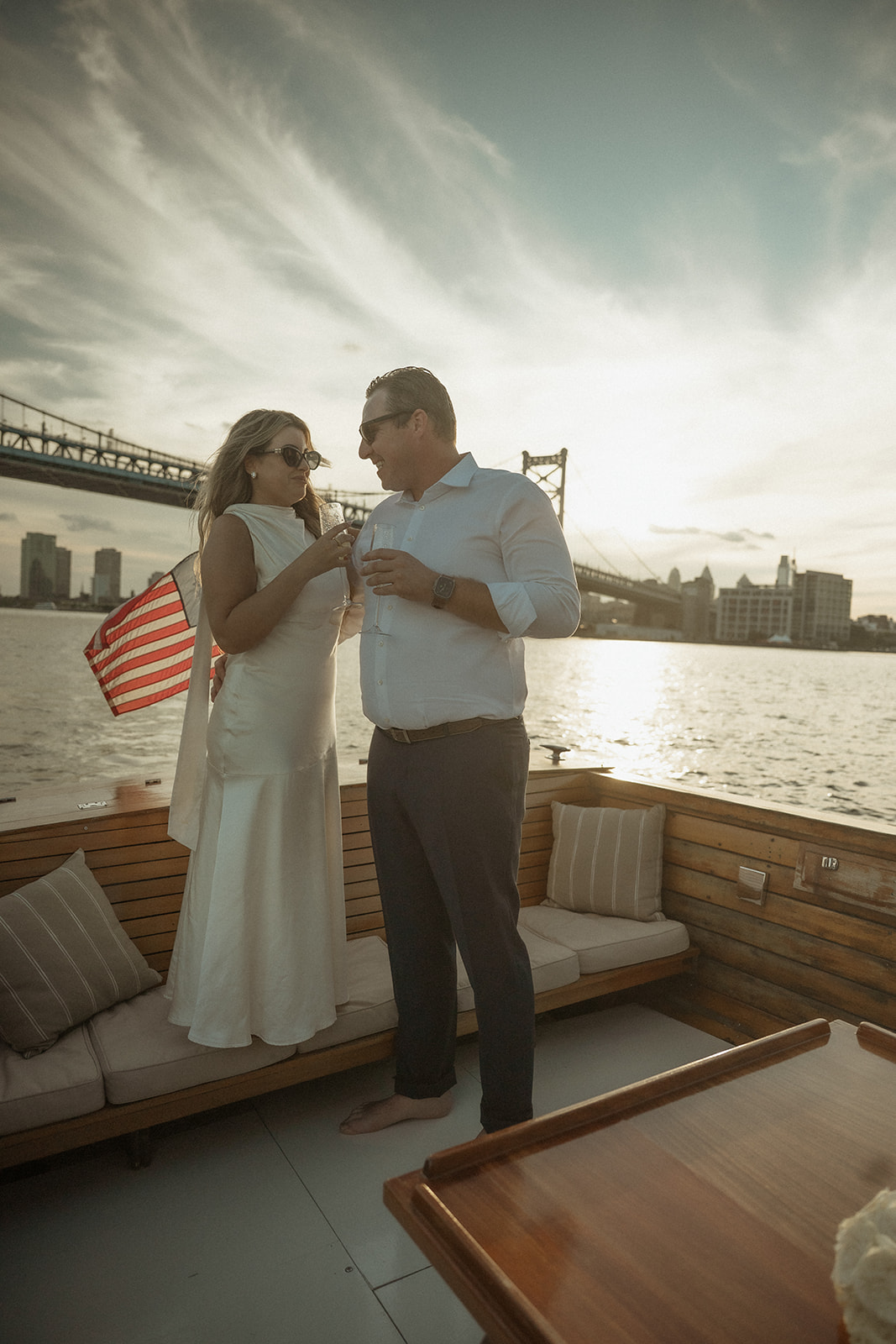 Couple having champagne during their sunset boat engagement photos in Philly