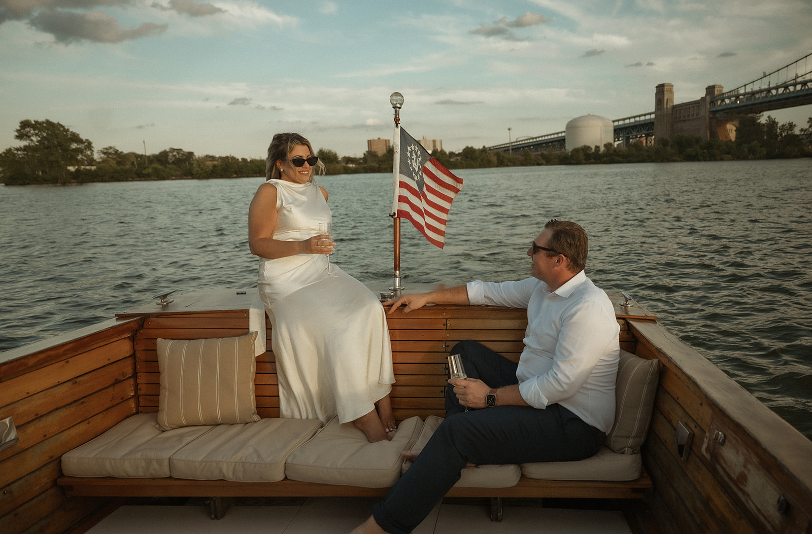 Couple enjoying champagne on the Argonaut with Sea Philly during a golden sunset engagement session on the water.