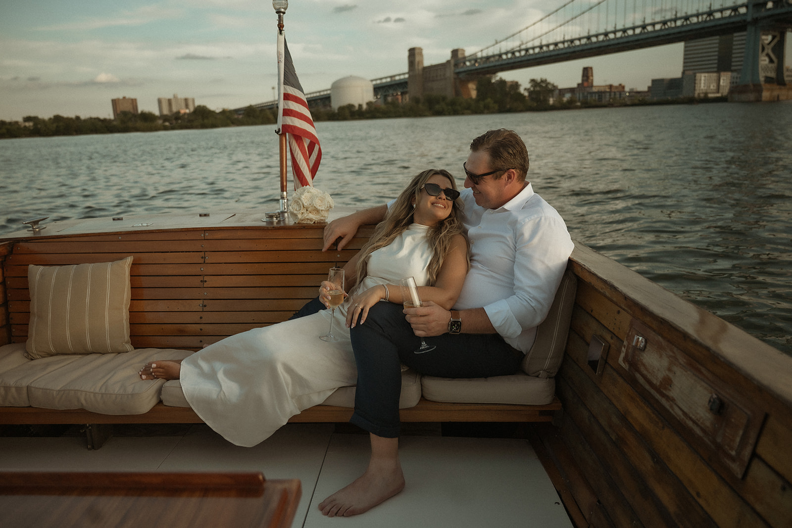 Couple drinking champagne on The Argonaut with Sea Philly during a golden sunset engagement session on the water.