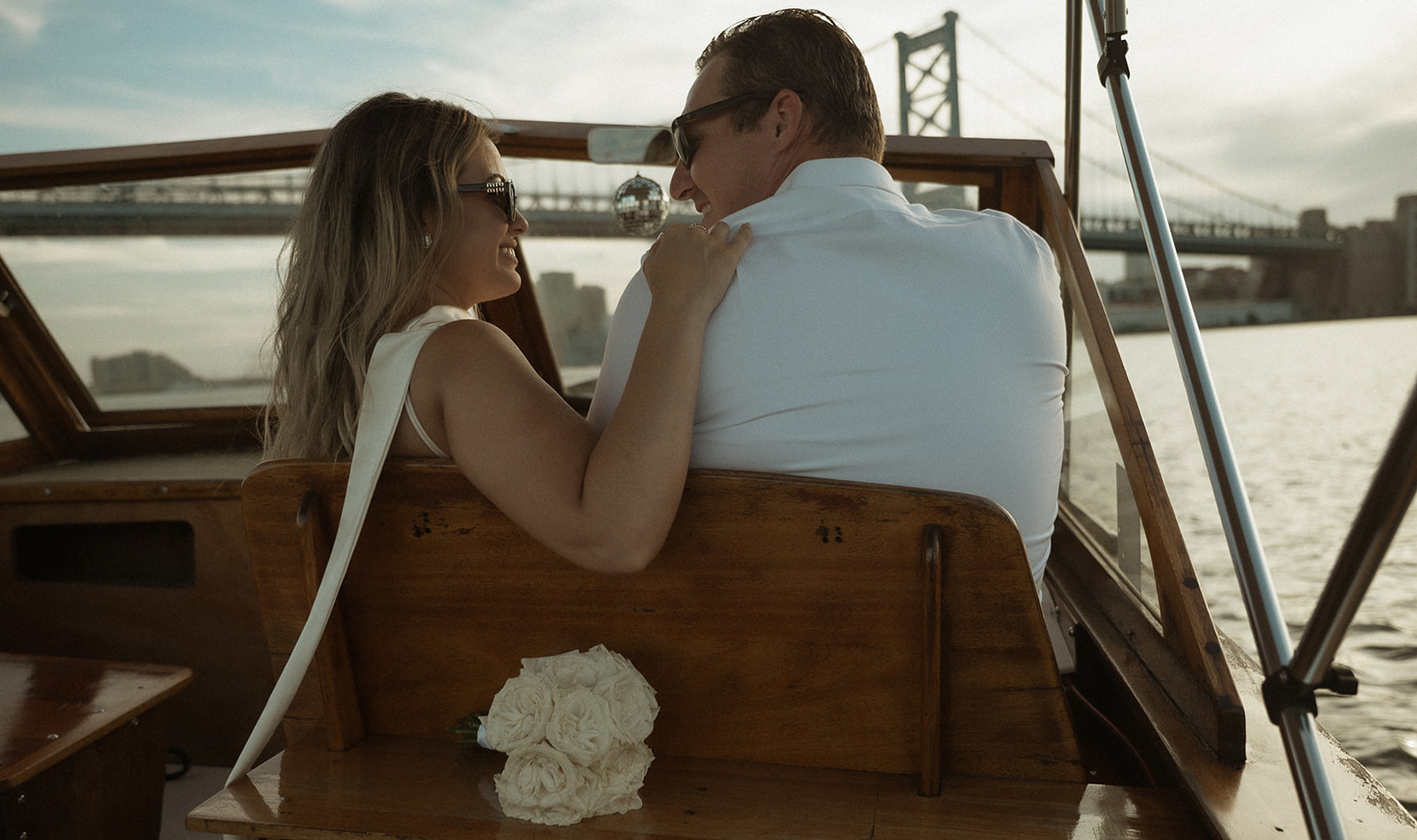 Couple steering the Argonaut with Sea Philly during a golden sunset engagement session on the water.