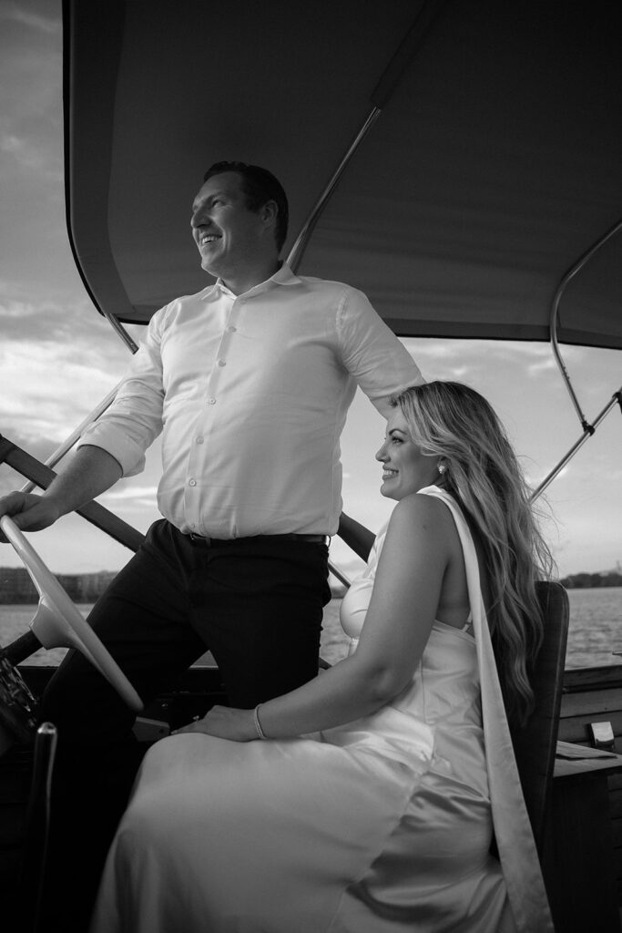Couple laughing and steering the boat together during their engagement photos in Philadelphia.
