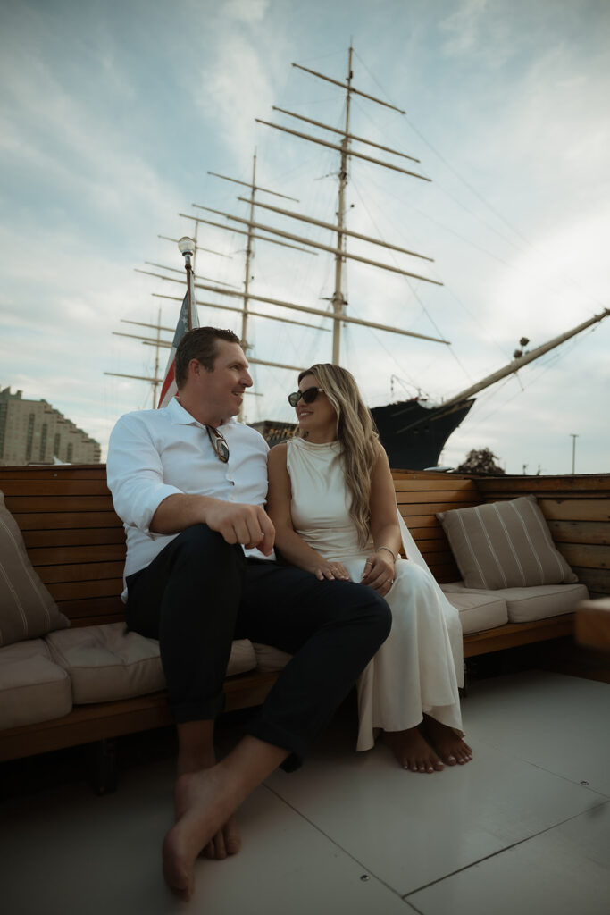 Couple sitting on he Argonaut with Sea Philly during a golden sunset engagement session on the water.