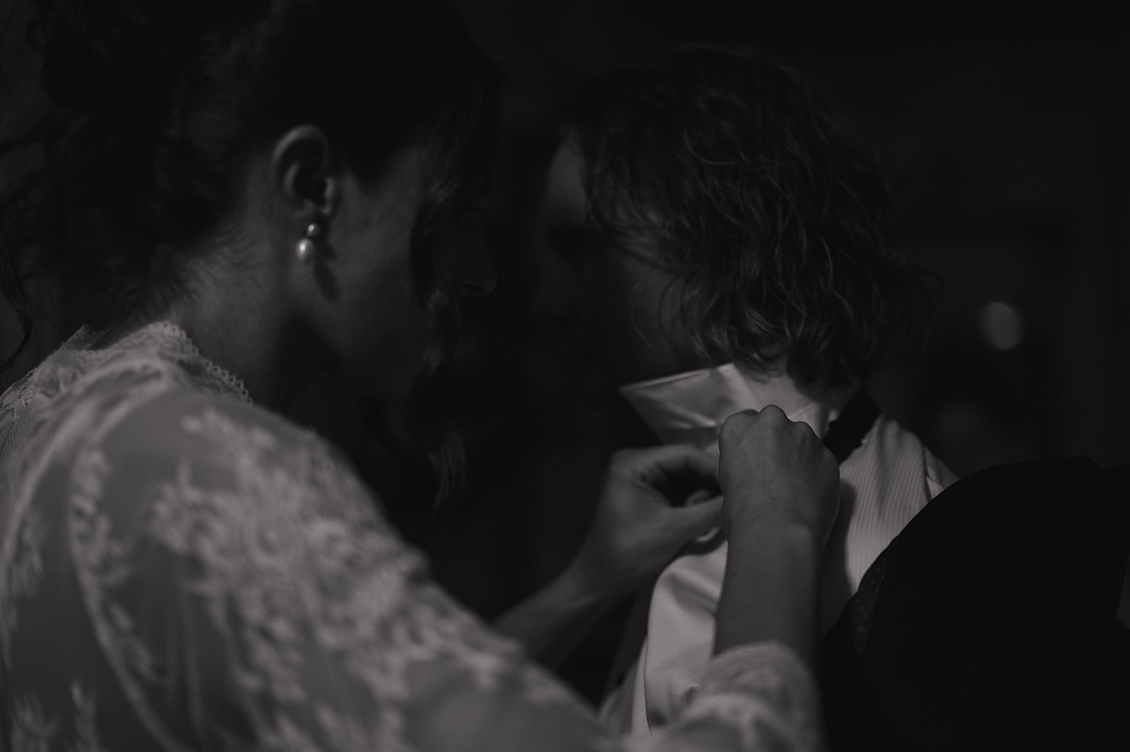 The bride gently fixes the groom’s collar and bowtie in soft shadows, a tender and emotive moment captured during their intimate New Jersey wedding photos.