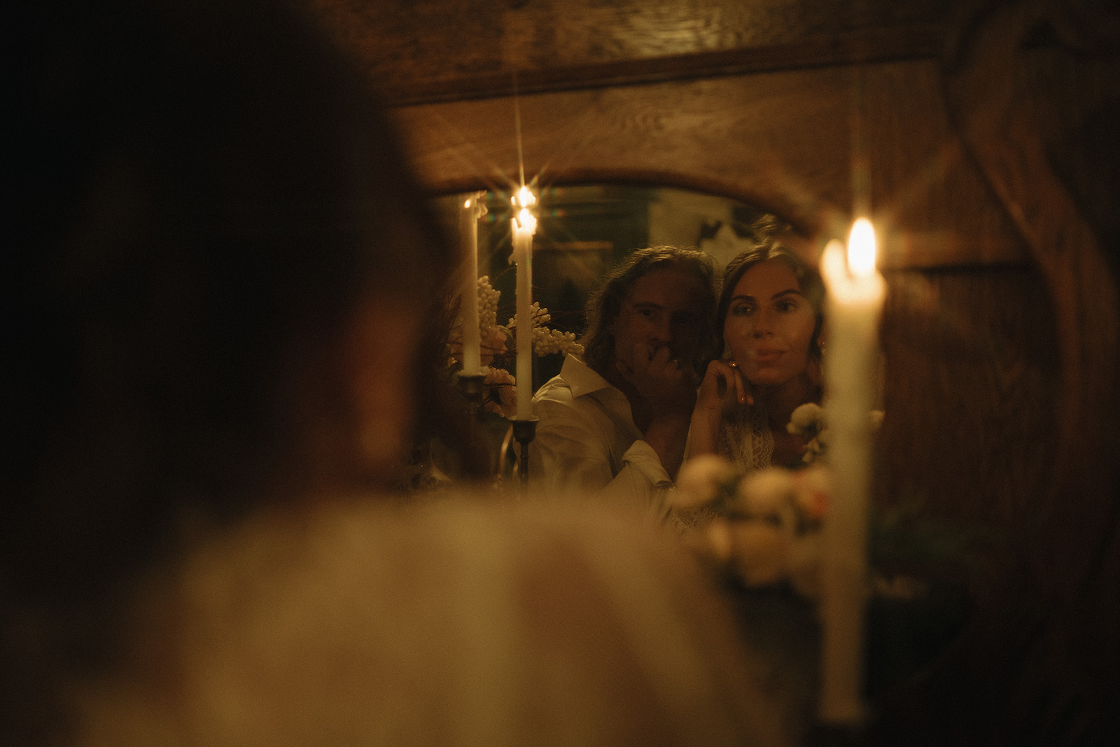 A warm, cinematic reflection of the couple in an antique mirror, surrounded by candlelight during their late-night intimate wedding photos in New Jersey.