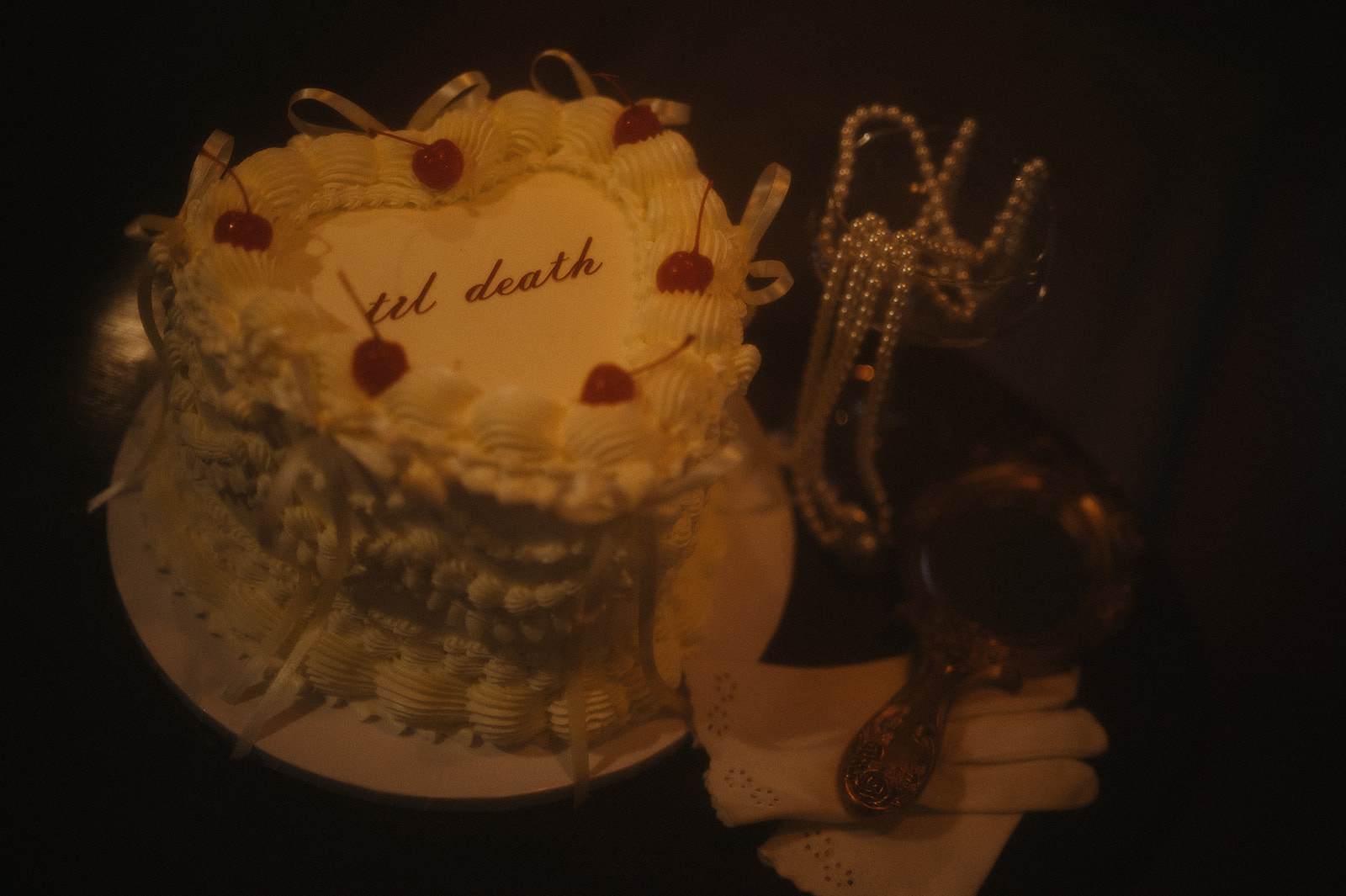 Retro-inspired still life of a vintage bakery-style cake with cherries, captured during late-night intimate wedding photos at River Witch Cottage.