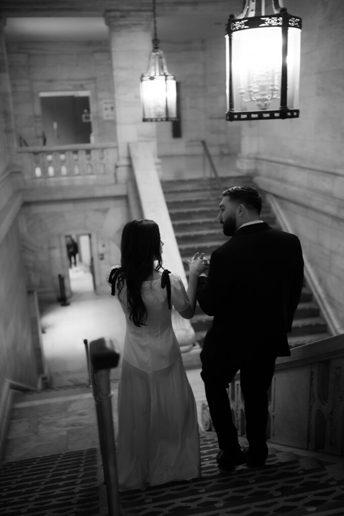 Black and white photo of a couple walking down the stairs during their New York Public Library engagement photos.