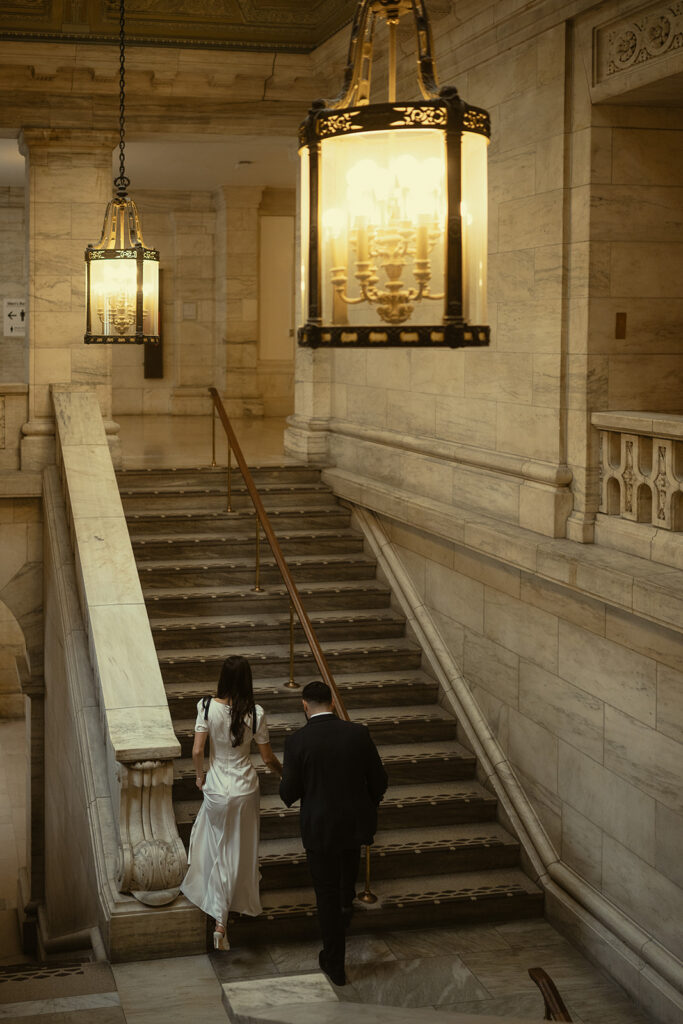 Couple walking up a staircase at the NY Public Library. 