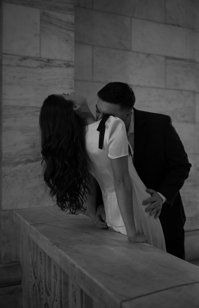 Man his his fiancés neck during their romantic New York Public Library engagement photos.