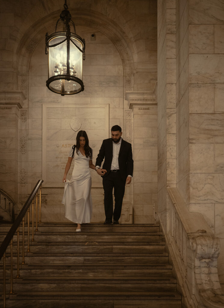 Couple holding hands and walking down a staircase together. 