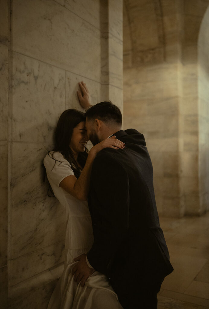 Couple leaning up against a wall at NY Public Library.
