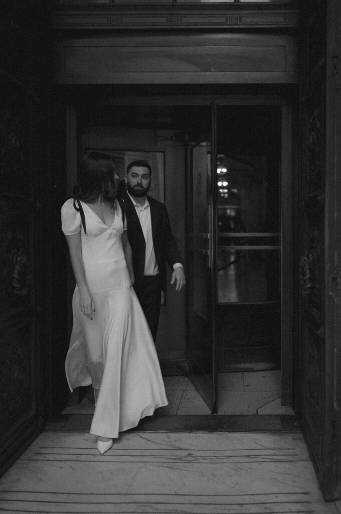 Black and white photo of a couple walking through a doorway.