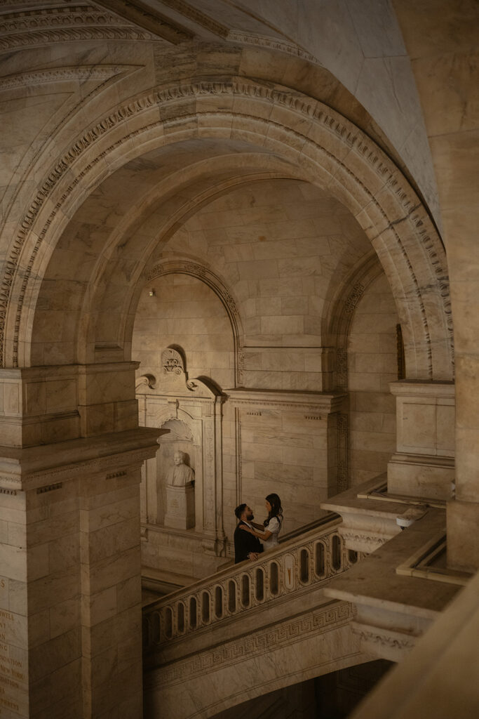 Couple posing on the staircase during their romantic New York Public Library engagement photos.