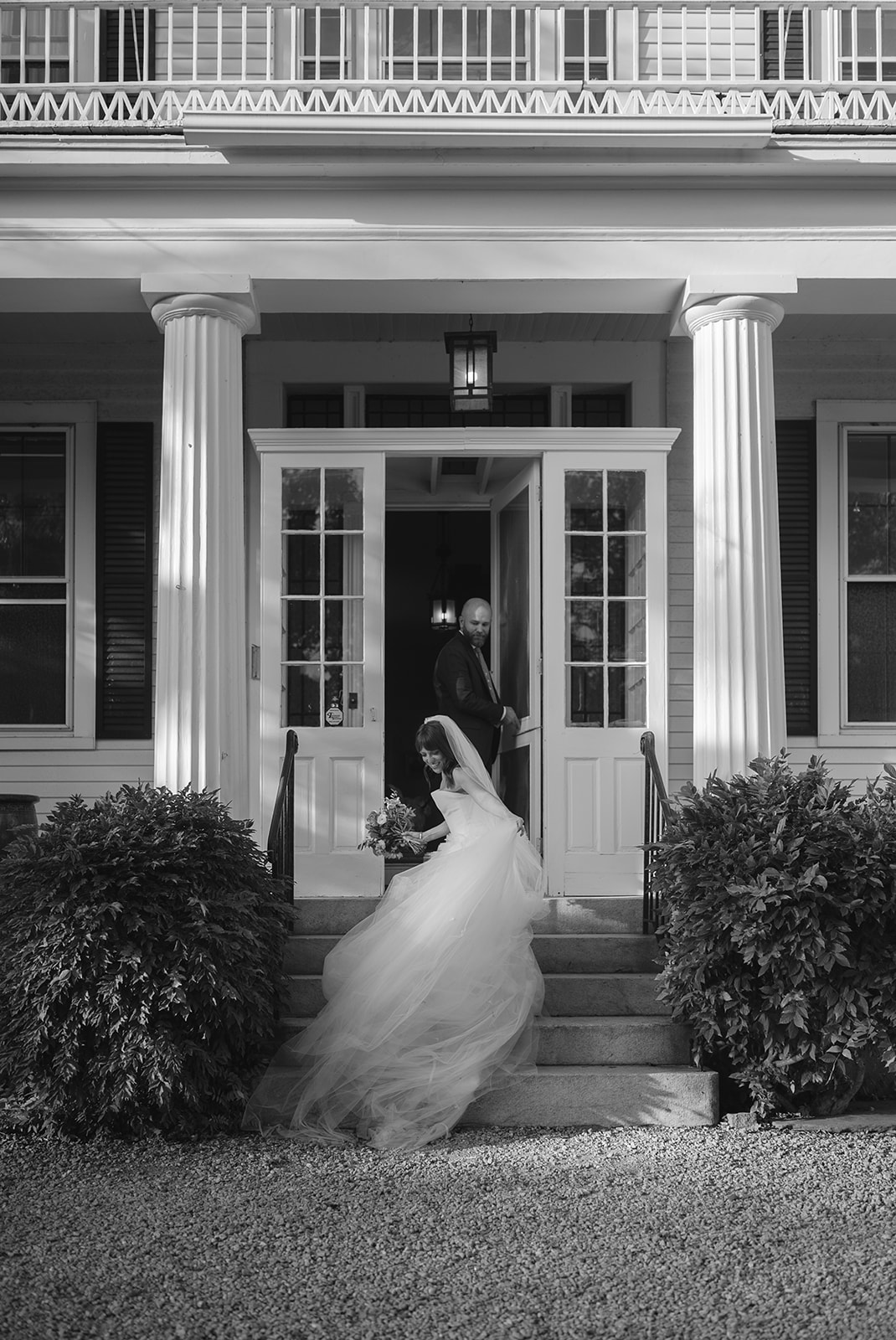 Bride stepping down manor house stairs with flowing veil during newlywed portraits at Stone Acres Farm wedding in Connecticut.