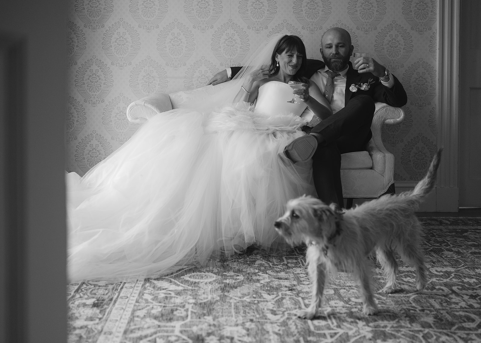 Bride and groom sitting with their dog in manor house room during Stone Acres Farm wedding portraits.