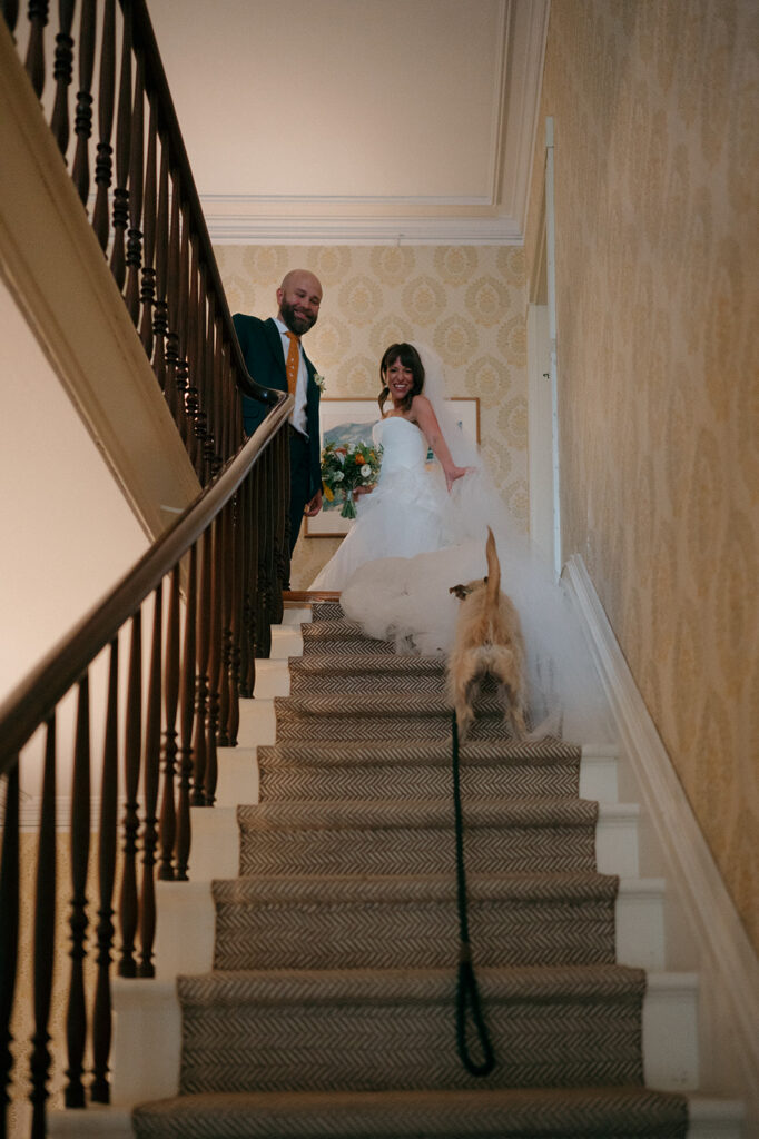 Bride and groom walking up the stairs at the Manor House at Stone Acres Farm with their dog. 