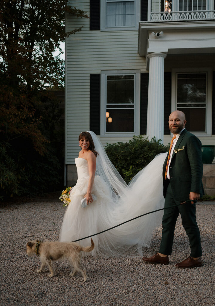 Bride and groom walking with their dog outside of the Manor House at Stone Acres Farm in CT. 