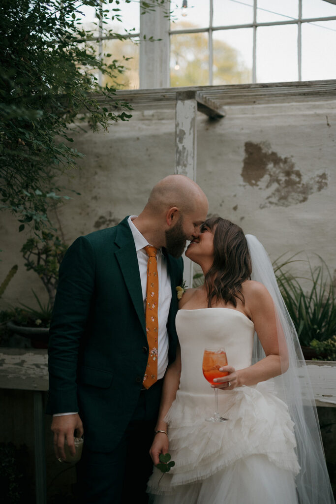 Bride and groom kissing inside greenhouse space during Stone Acres Farm wedding newlywed portraits.