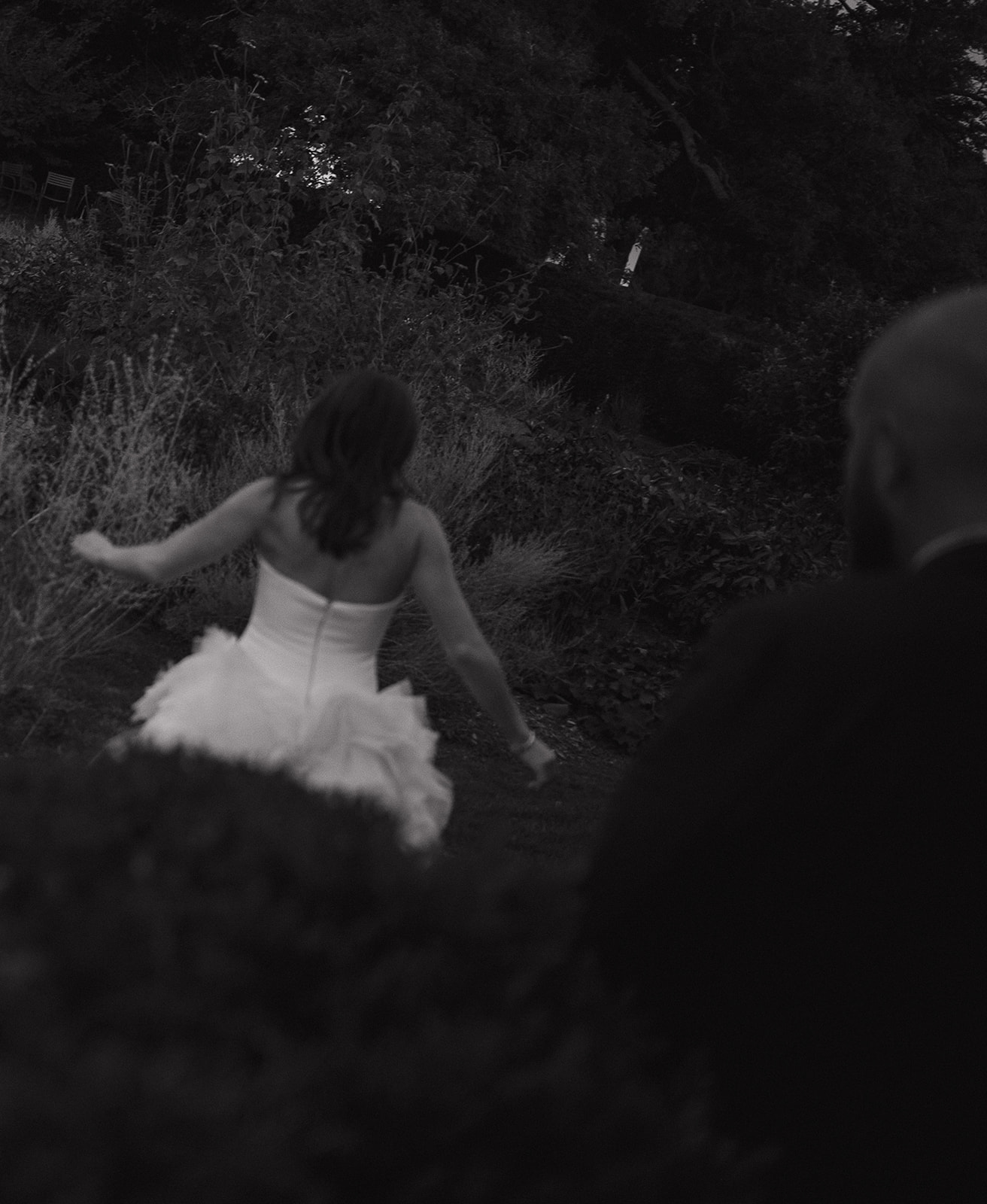 Romantic black and white garden portrait of bride running through greenery at Stone Acres Farm wedding venue.