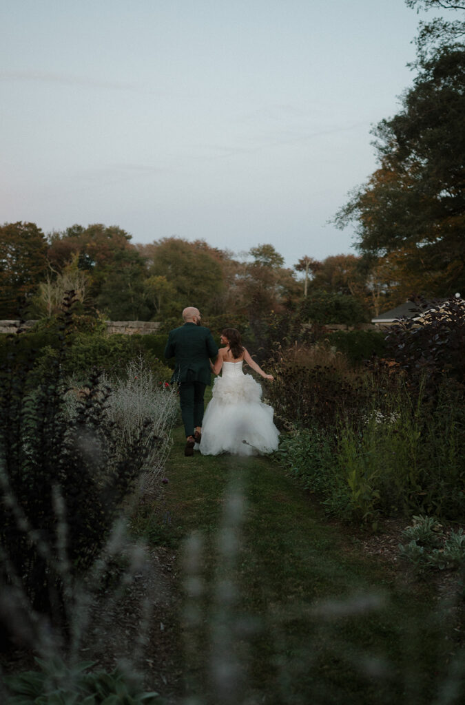 Bride and groom walking hand in hand through garden path at Stone Acres Farm wedding portraits.