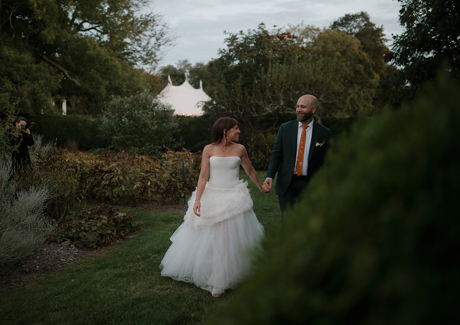 Bride and groom walking hand in hand through garden path at Stone Acres Farm wedding portraits.