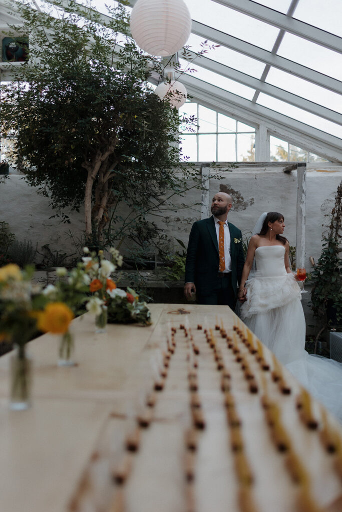 Bride and groom holding hands inside greenhouse space during Stone Acres Farm wedding newlywed portraits.