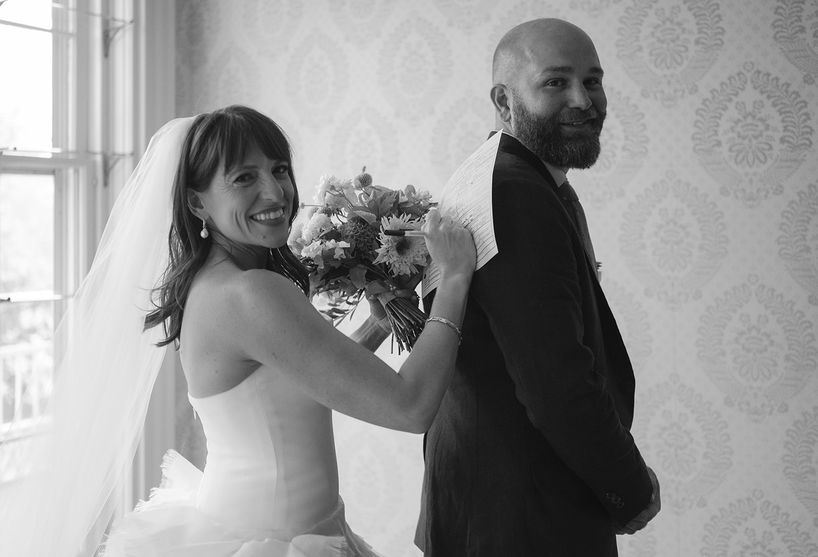 Bride signing her marriage license on her grooms back. 