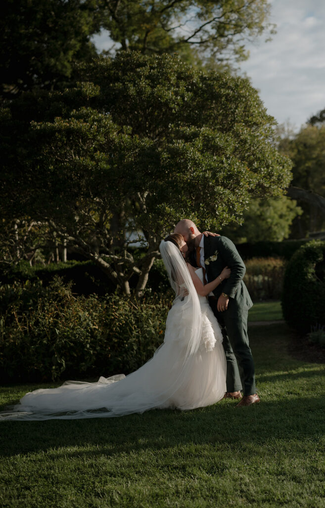 Romantic first kiss during outdoor Boxwood Garden ceremony at Stone Acres Farm wedding.