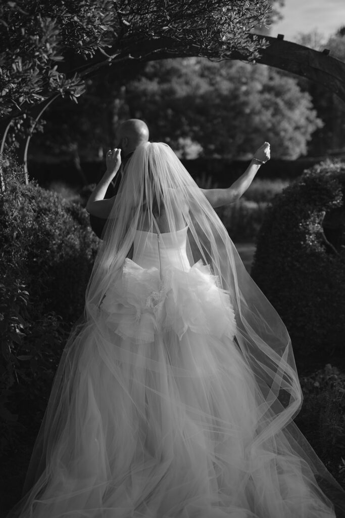 Black and white photo of a bride and groom walking through the gardens at Stone Acre Farms. 