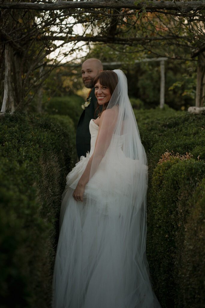 Bride and groom walking through the Boxwood Gardens at Stone Acres Farm. 