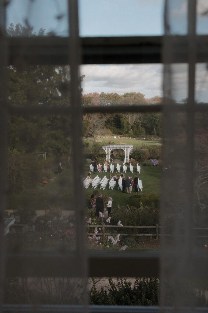 Candid wedding ceremony photo through the window at Manor House at Stone Acres Farm. 