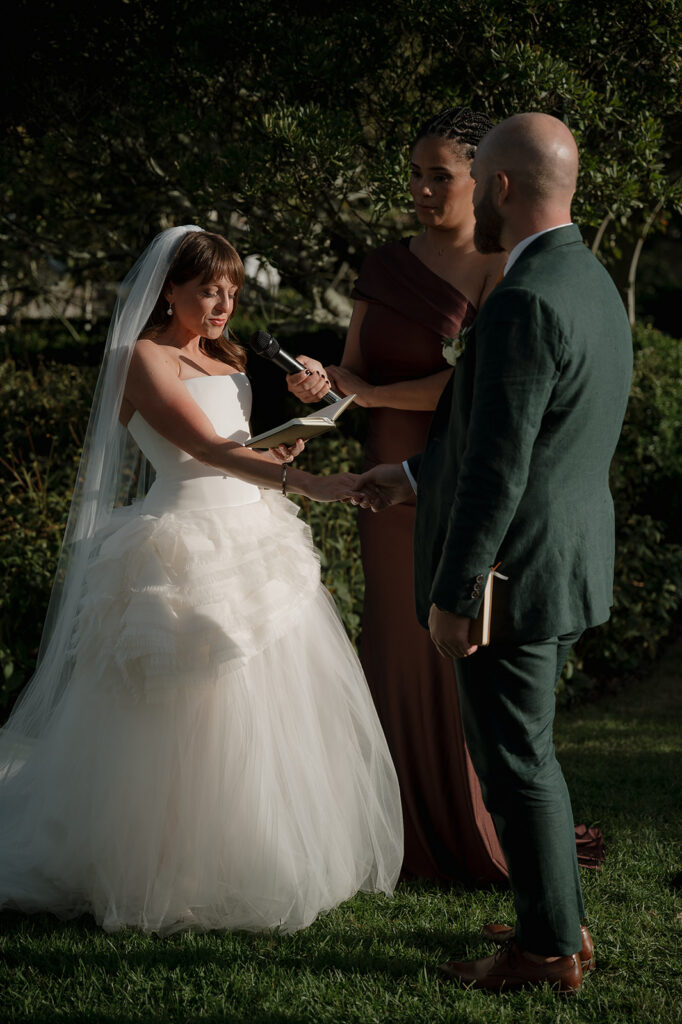 Bride and groom holding hands while exchanging vows in Boxwood Garden ceremony at Stone Acres Farm wedding.