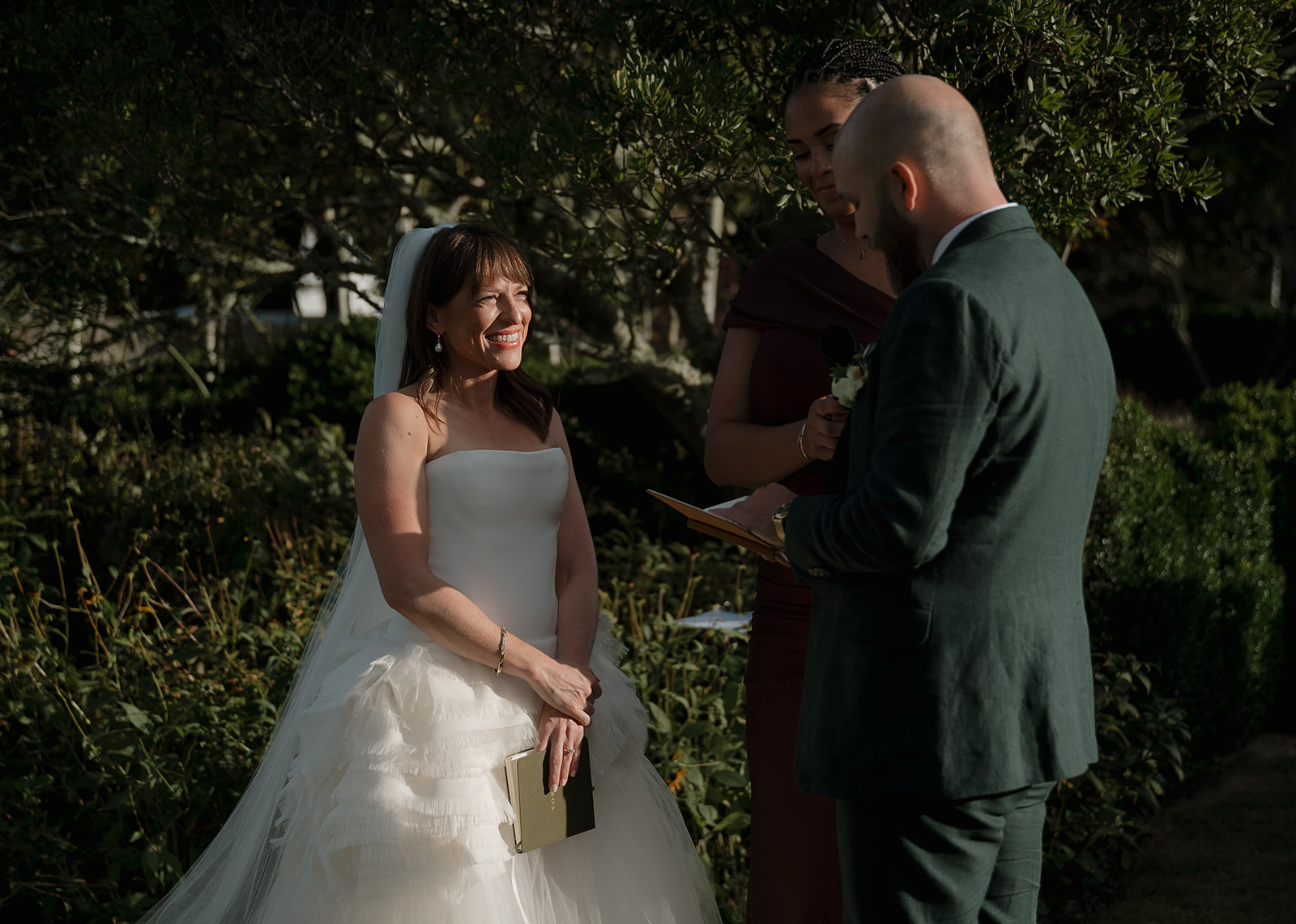 Bride smiling at groom while exchanging vows in garden ceremony at Stone Acres Farm.