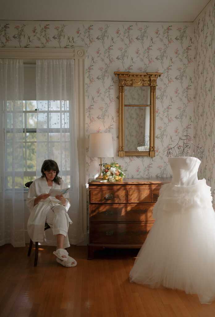 Bride reading a handwritten note beside her Vera Wang dress in elegant getting ready room at Stone Acres Farm wedding.