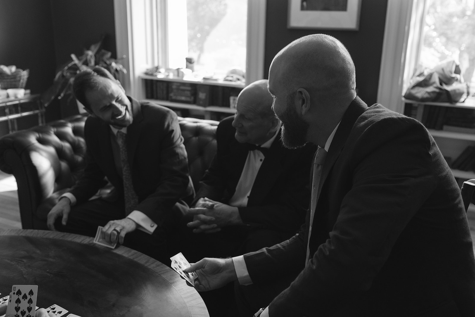 Groomsmen playing cards together inside historic farmhouse during Stone Acres Farm wedding morning.