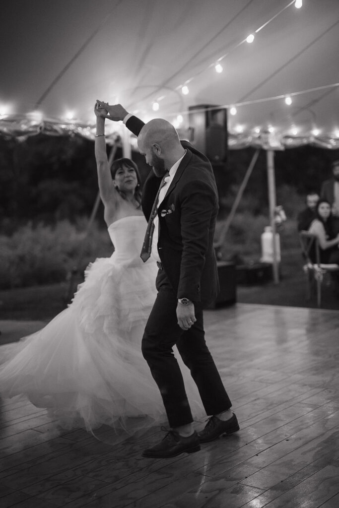 Newlywed first dance under string lights during tented reception in The Meadow at Stone Acres Farm.