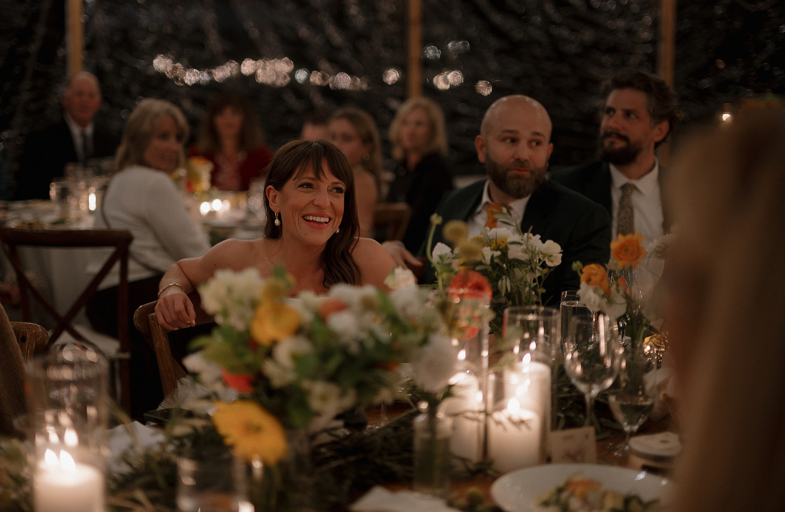 Bride smiling during wedding reception speeches. 