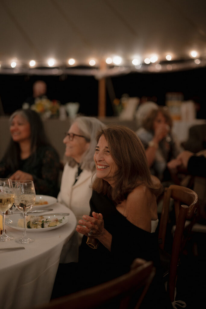 Brides mother smiling during speeches.