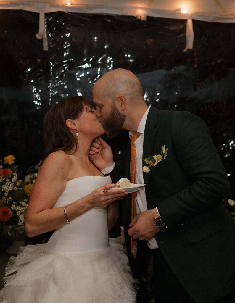 Bride and groom sharing cake during reception inside tented pavilion at Stone Acres Farm wedding.